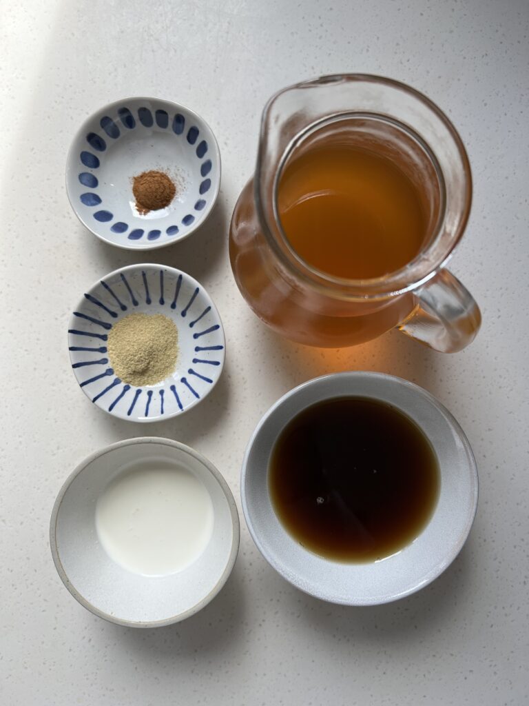 Ingredients for the Served Seasonal Orange and Cardamom Iced Tea Latte. Ground cinnamon, ground cardamom, heavy cream, orange rooibos and chai iced tea, maple syrup.