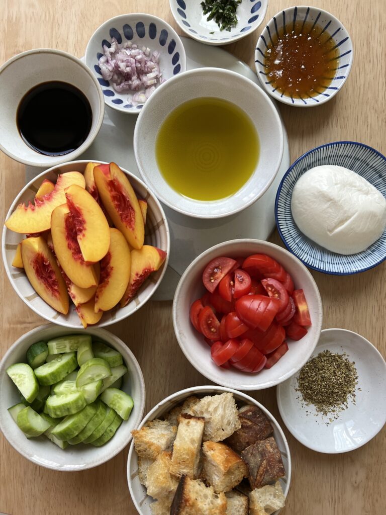 Ingredients for Served Seasonal Summer Panzanella Salad. Nectarines, tomatoes, cucumbers, sourdough bread, olive oil, herby balsamic vinaigrette, salt and pepper. 