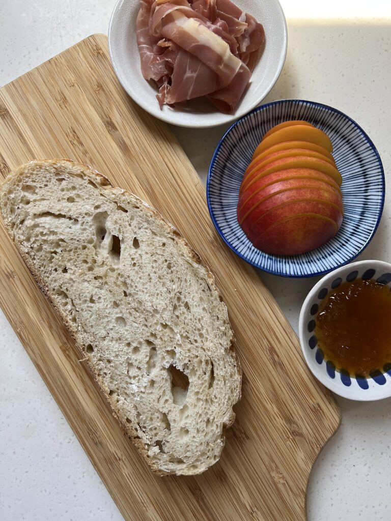 Ingredients for Served Seasonal Nectarine and Buratta Summer Toast. Sourdough bread, prosciutto, sliced nectarines and fig preserves.