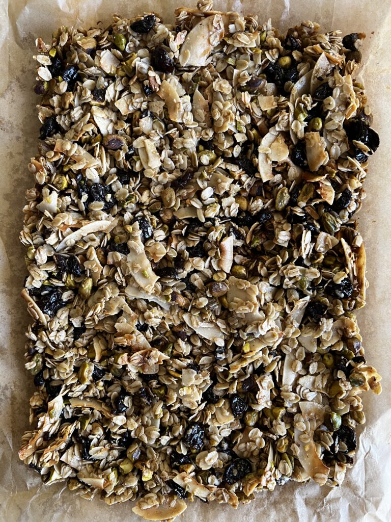 Freshly made Served Seasonal Cherry and Cardamom Roasted Granola on parchment paper.