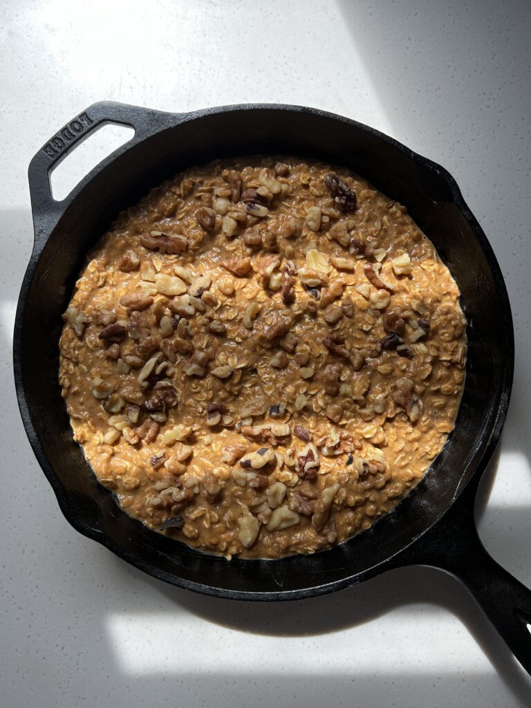 Served Seasonal Pumpkin Oatmeal Bake before baking in a cast iron pan topped with chopped walnuts. 