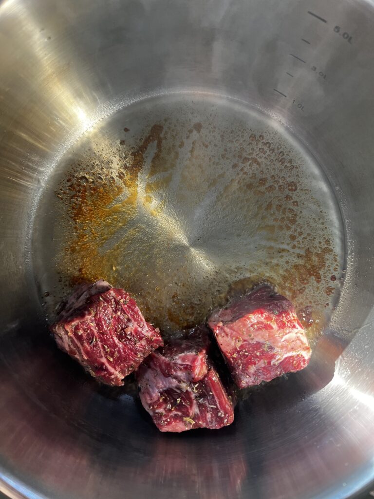 Sugar turned amber and beef cubes beginning to sear.